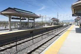 Empty train station platform with shelters and train tracks, clear sky in the background.