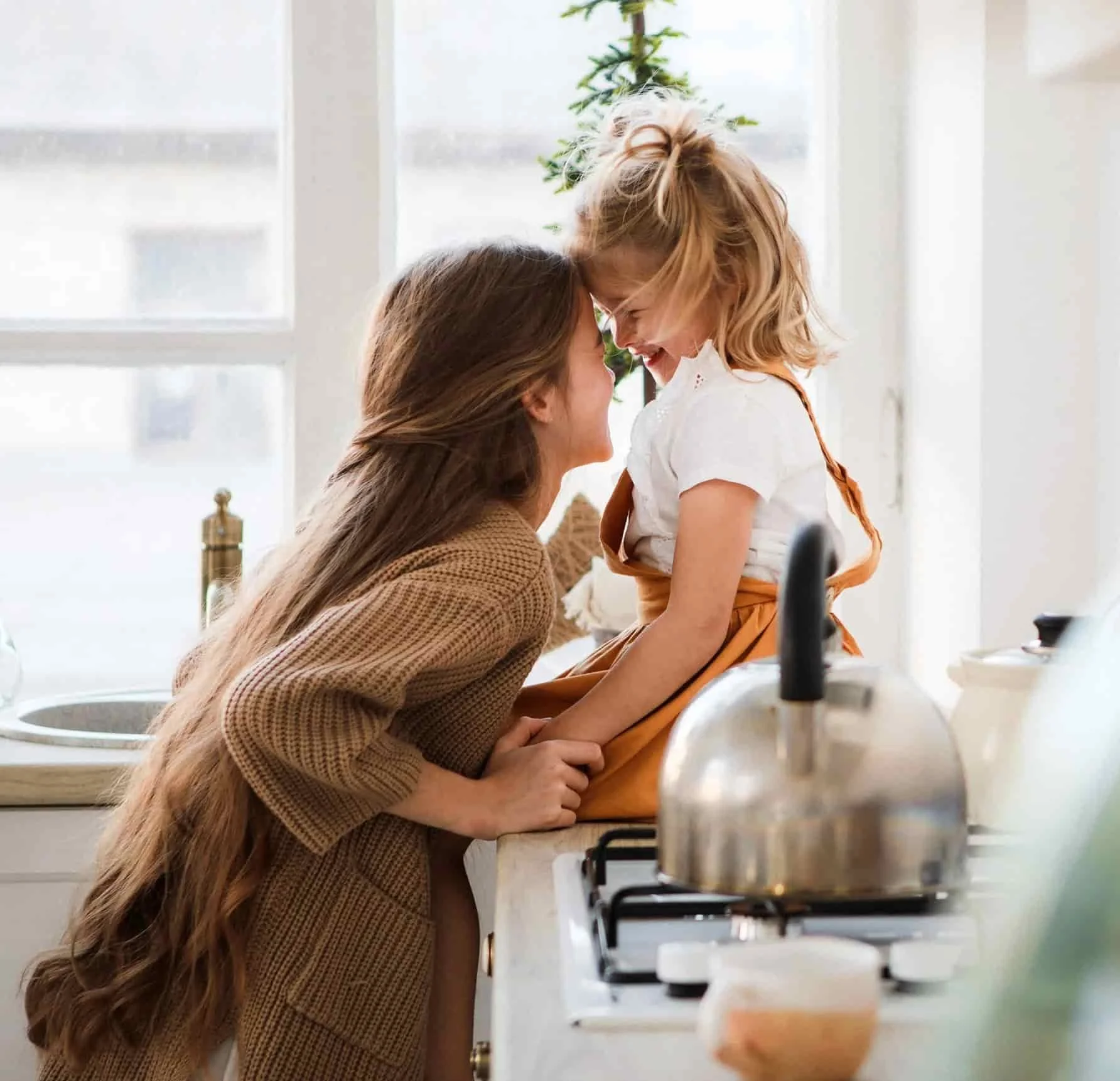 two adolescent sisters lovingly embracing and smiling in apartment kitchen