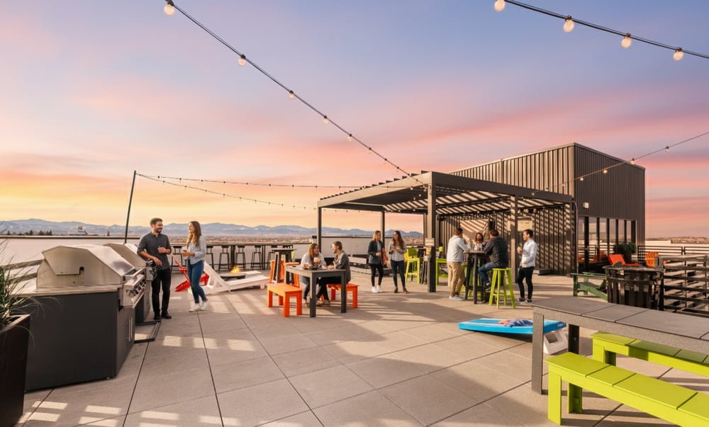 Rooftop patio with outdoor furniture, colorful seating, string lights, grills, and a scenic mountain view under a blue sky.