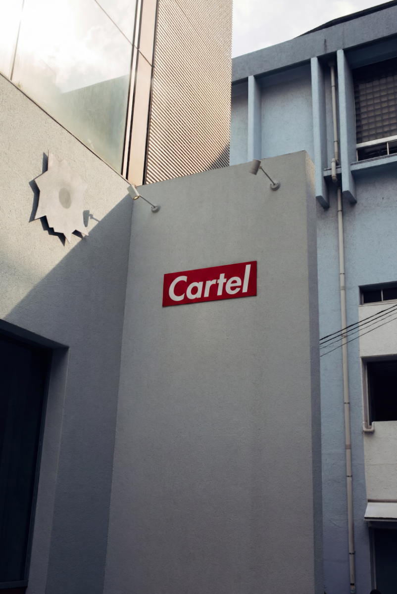 Close-up of a building exterior with a red sign reading 'Cartel' and a stylized black and white star-shaped logo.