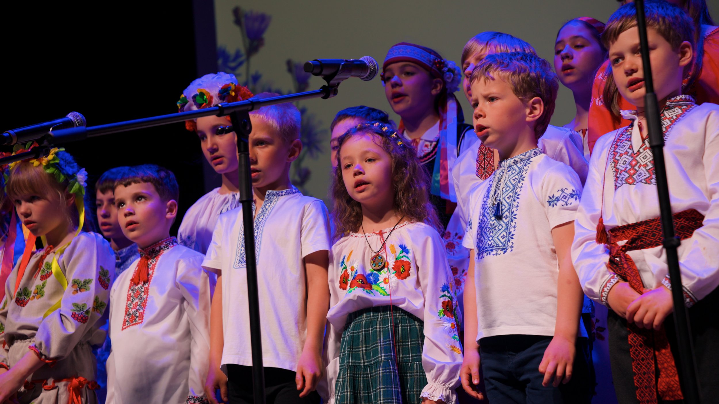Children dressed in traditional Ukrainian clothing perform on stage during a cultural event.