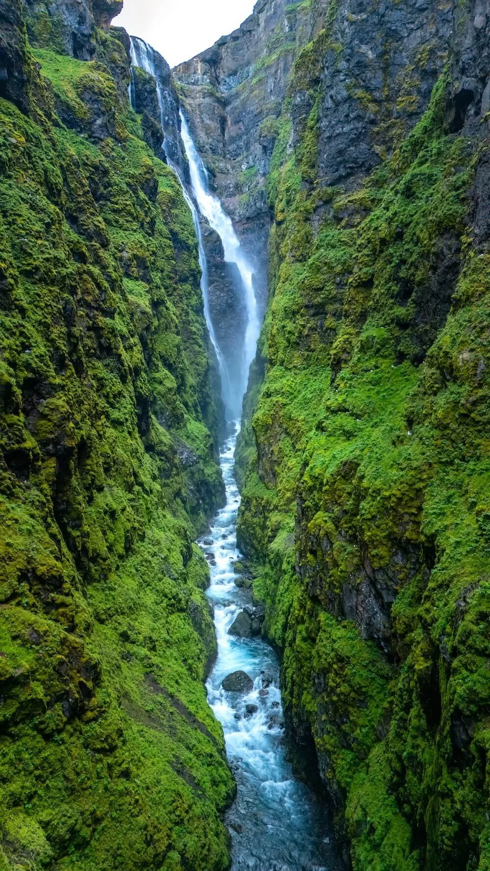 Waterfall moving through a narrow, moss-covered canyon, symbolizing release and movement