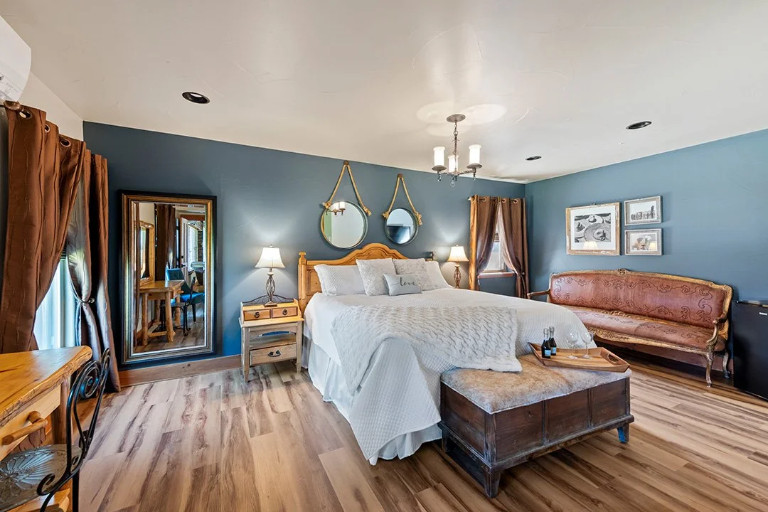 Luxurious guest suite with premium white linens and comfortable leather couches at a Colorado barn wedding venue with onsite lodging