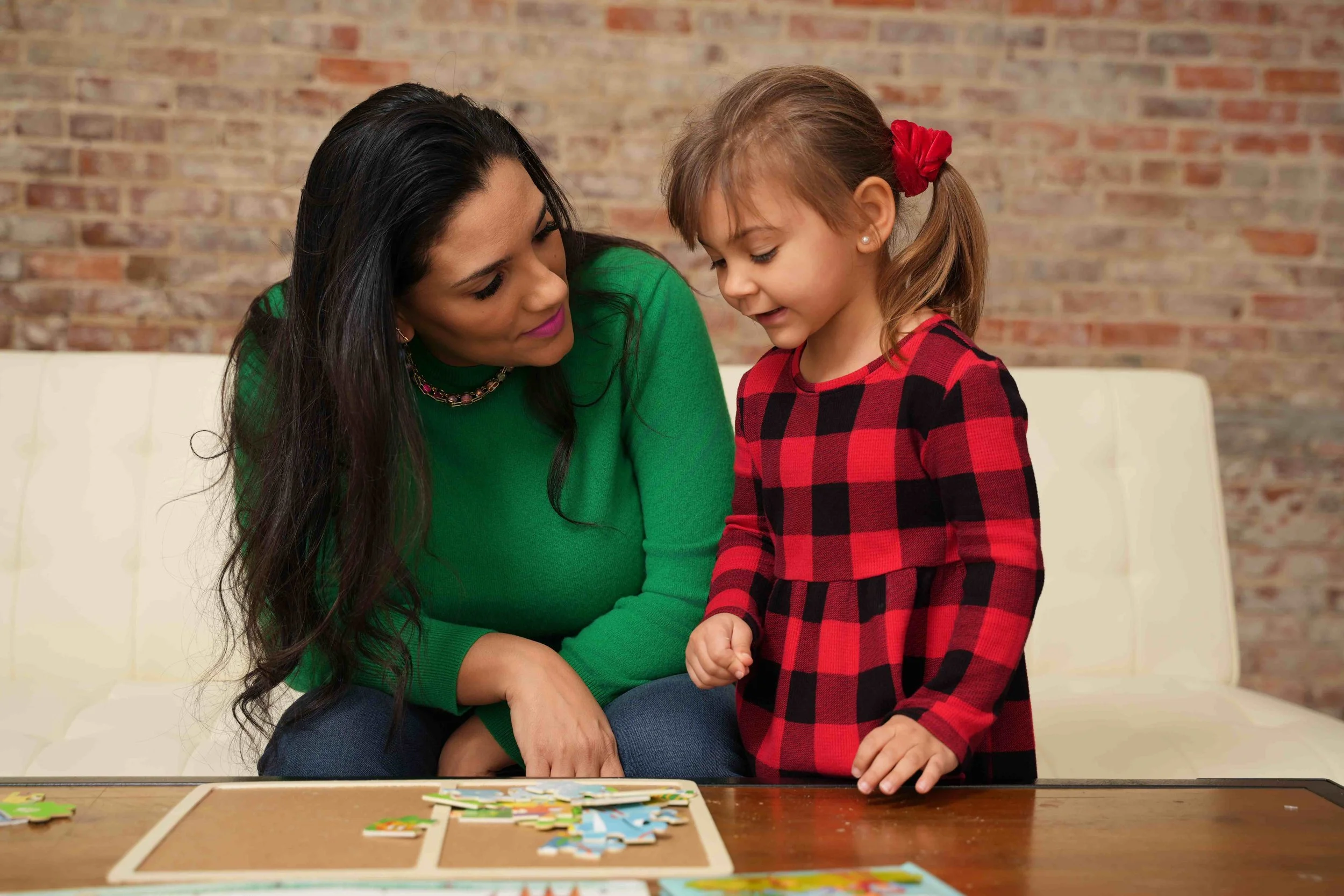 A pediatric occupational therapist and a young girl playing a puzzle game together at a table while working on fine motor skills during occupational therapy for kids in Laurinburg, NC.
