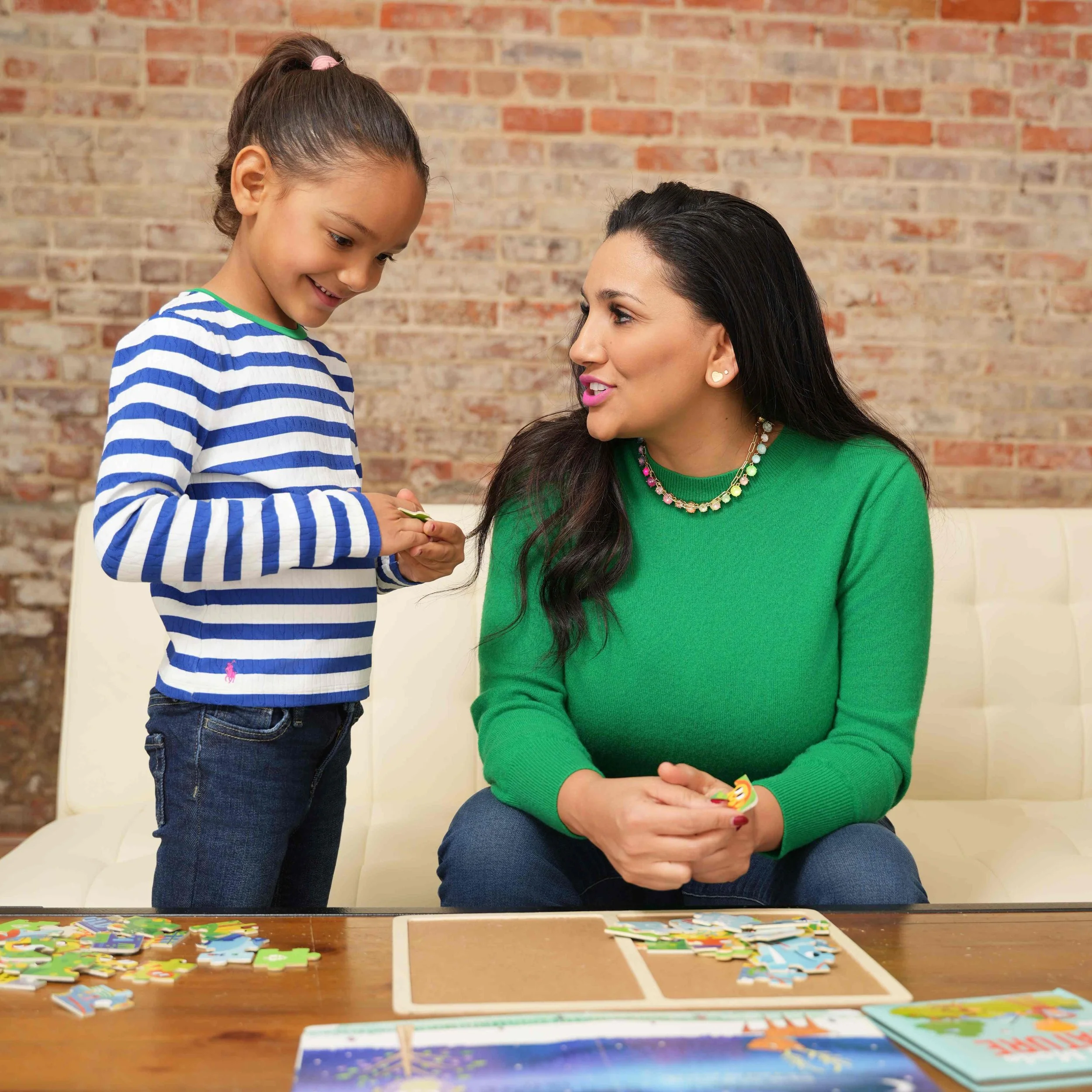 A speech therapist and a young girl are sitting at a table playing a game while working on language skills during speech therapy for children in Laurinburg, NC.