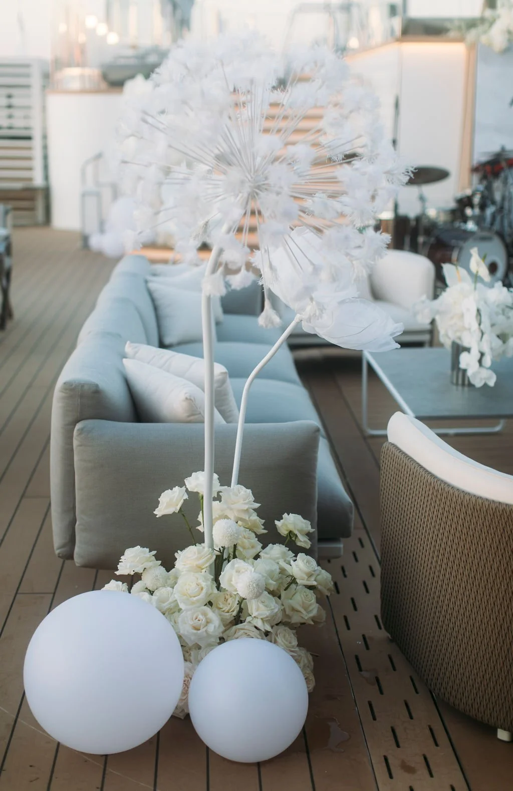 Decorative white floral arrangement with illuminated spherical lights on a wooden deck, featuring white roses, spherical balls, and fluffy flower-like decorations.
