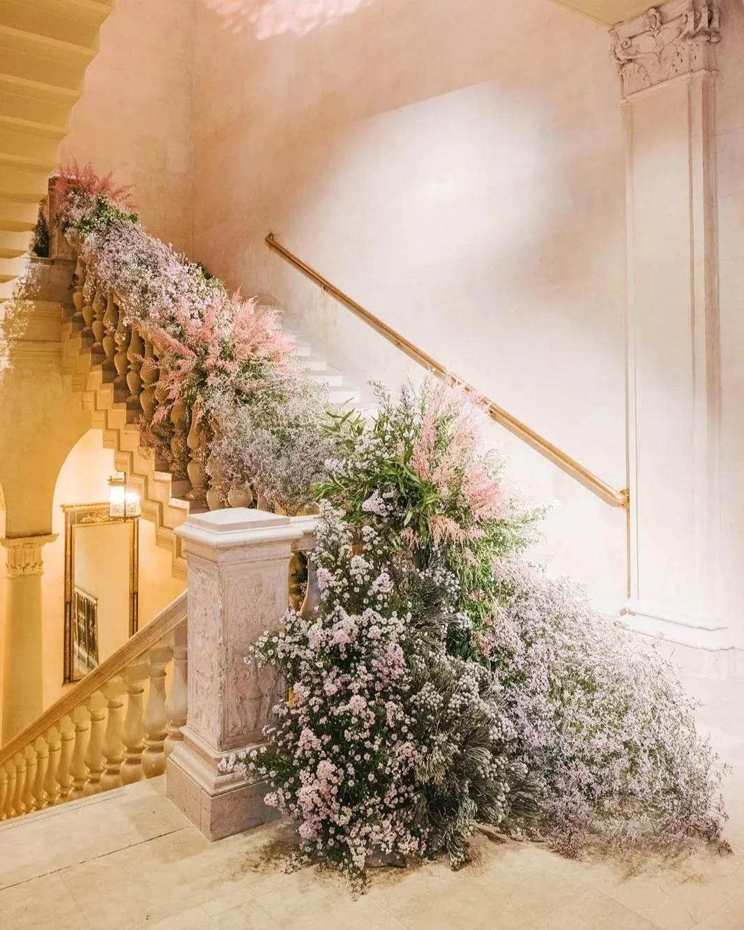 Indoor staircase decorated with pink and white flowers and greenery.