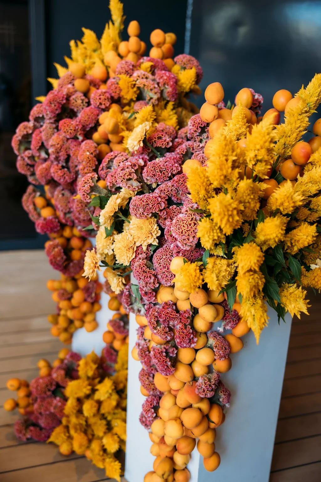 Colorful floral arrangement with pink and yellow flowers and orange berries in a white vase.