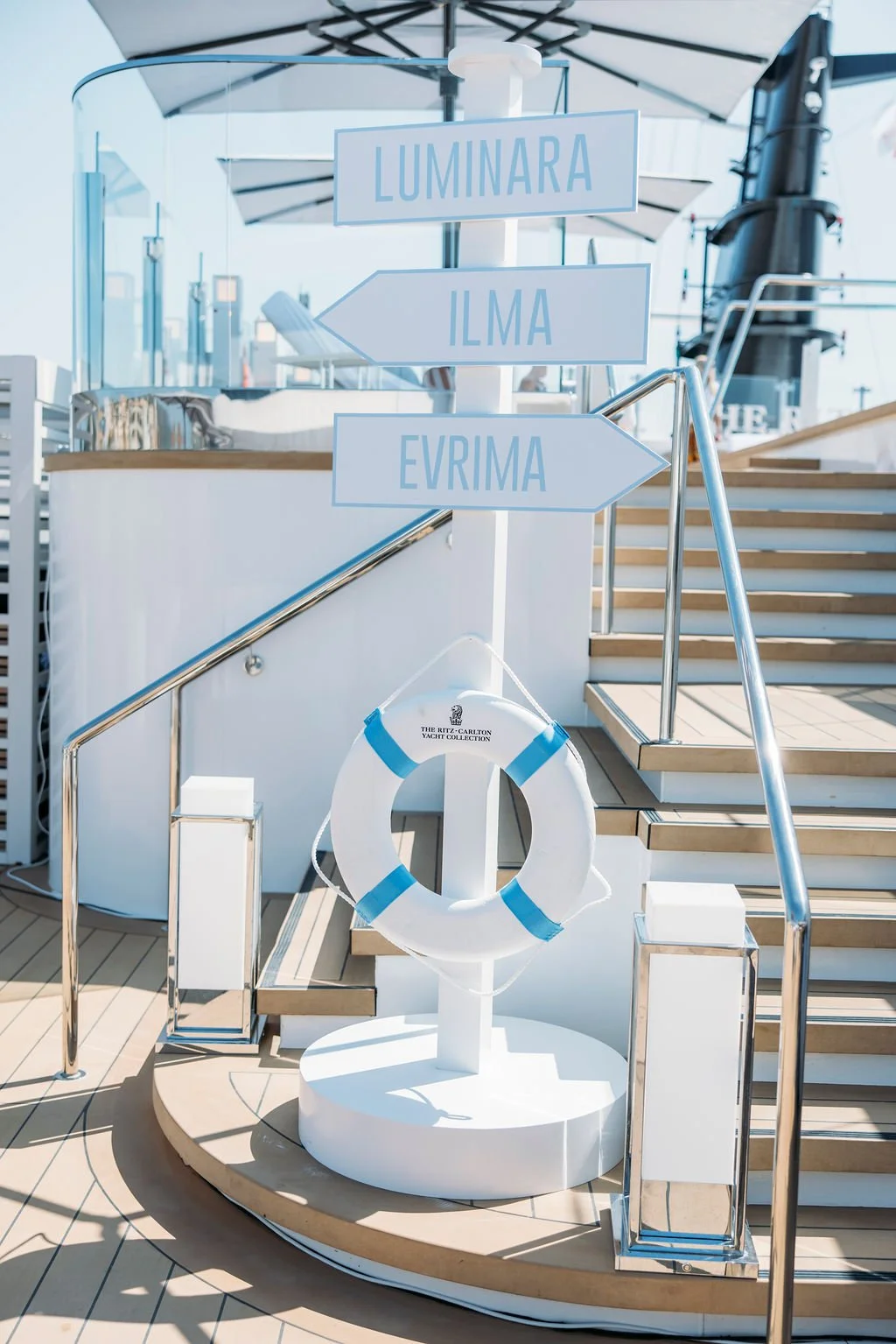 Signpost with directional arrows pointing to LUMINARA, ILMA, and EVRIMA on a cruise ship deck.