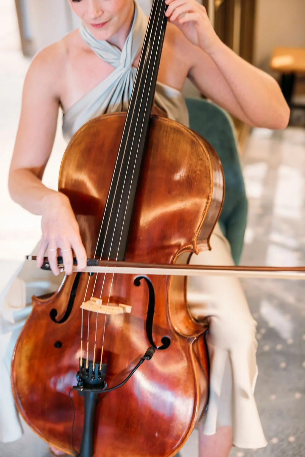 A woman playing a cello, focusing on her hands and the instrument.