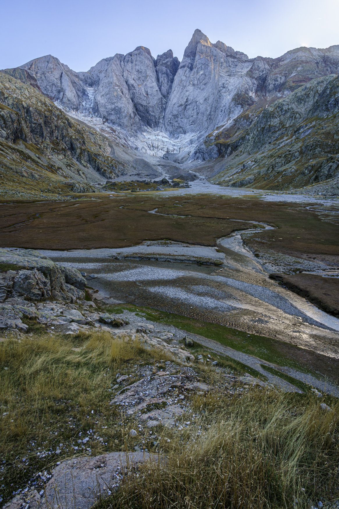 Bergmassiv des Vignemale mit Gletscher zu Füßen. Davor eine Prairie mit Wildwasserbett und Gräsern