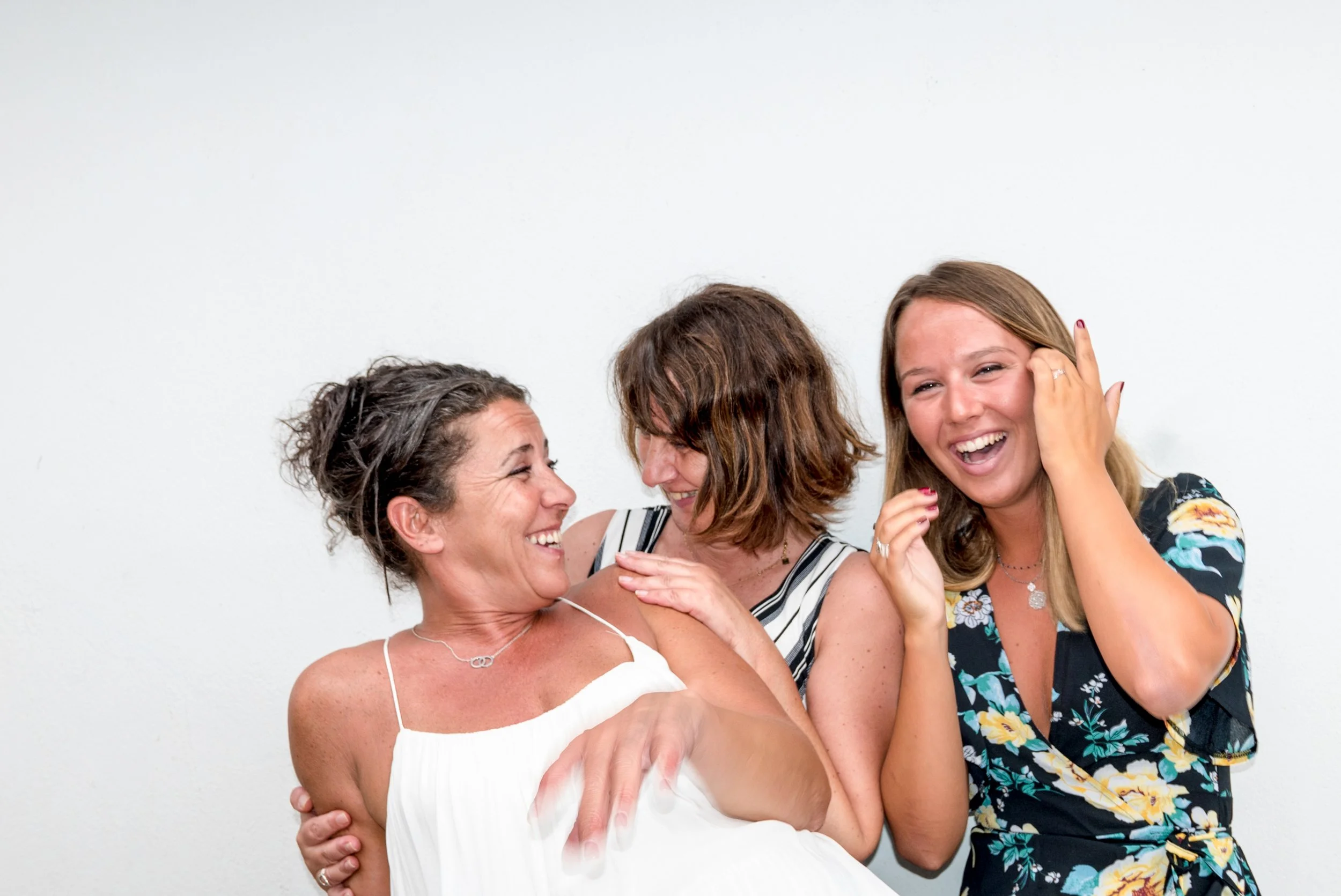 Drei junge Frauen albern sitzend mit einander. Sie sind festlich gekleidet.