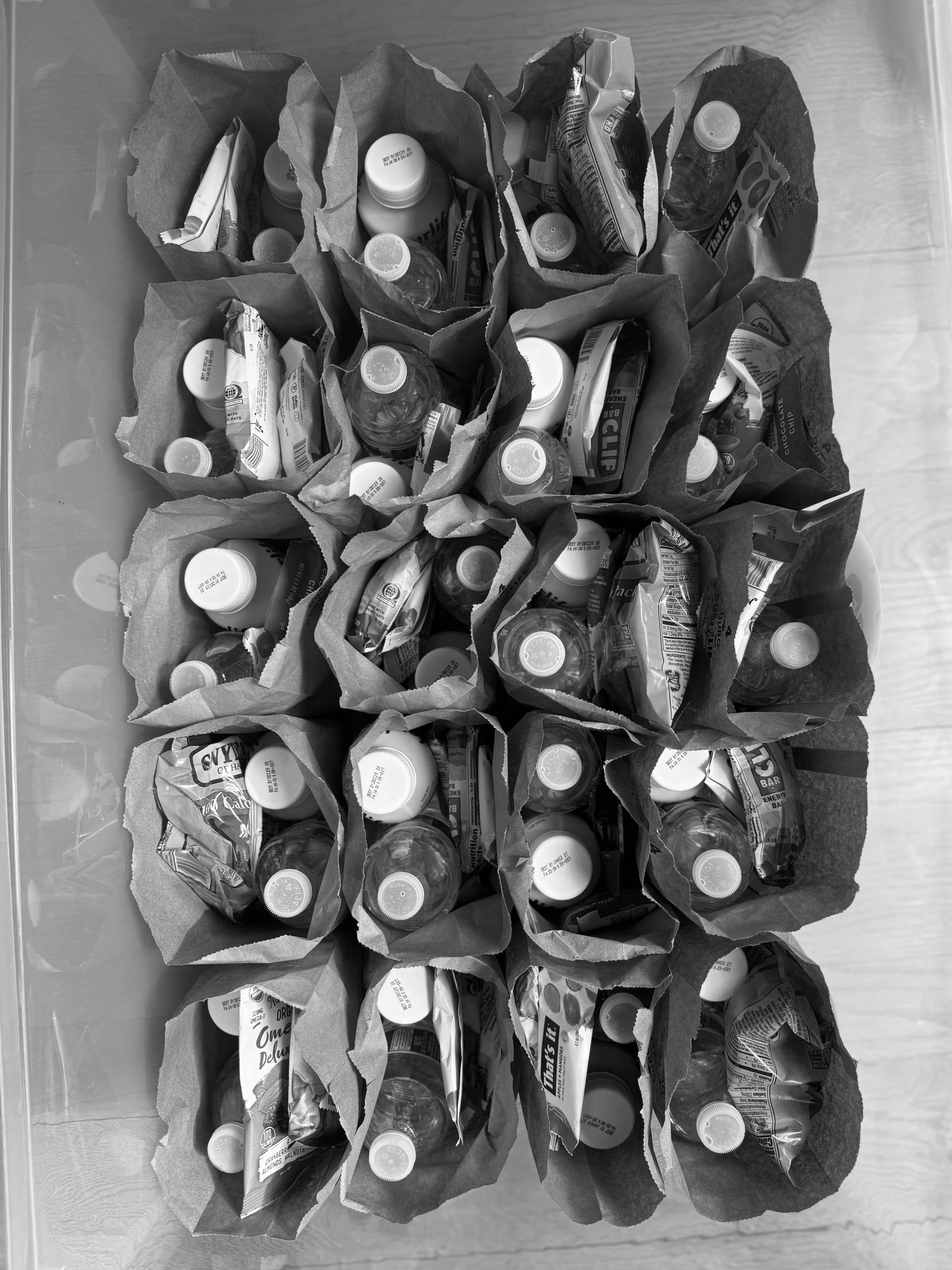 Multiple teen snack bags filled with bottled water, protein shakes, and snack items.