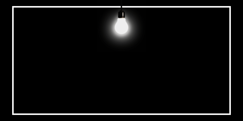 A glowing incandescent light bulb hanging from a black cord in a dark room, with a white border around the image.