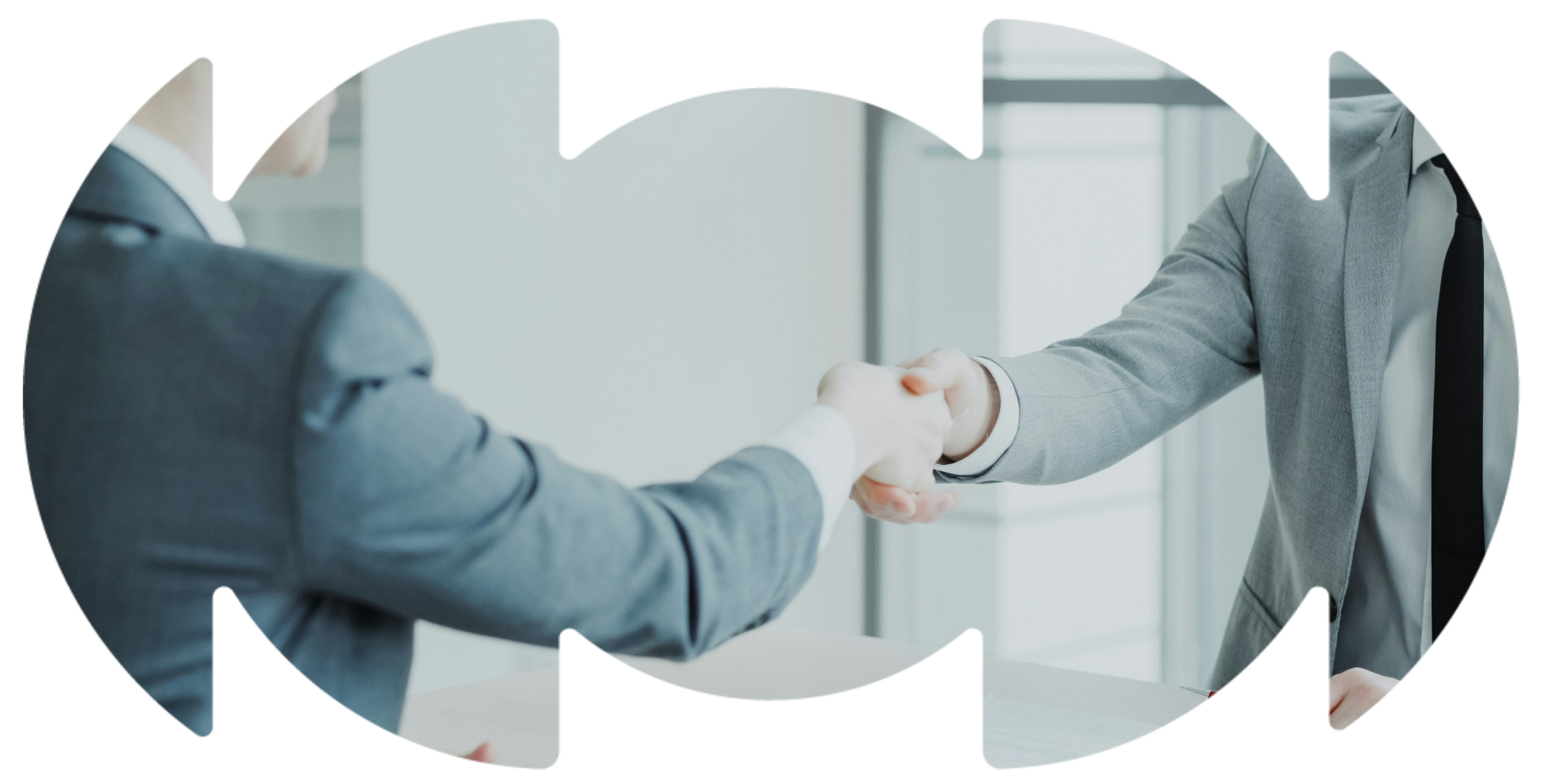 Two people in suits shaking hands in a business office setting.