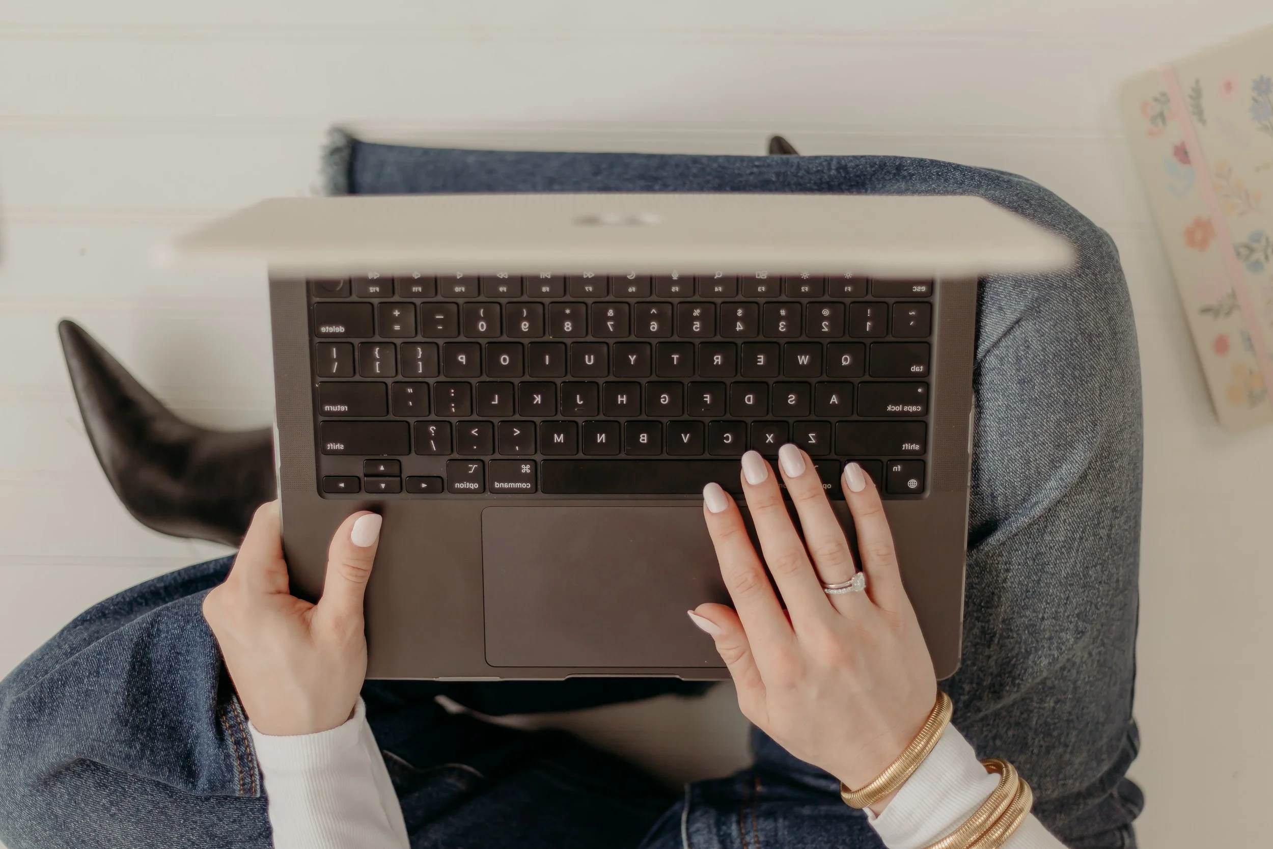 Overhead view of a person using a laptop on their lap, hands on keyboard, sitting on a blue cushion or chair.