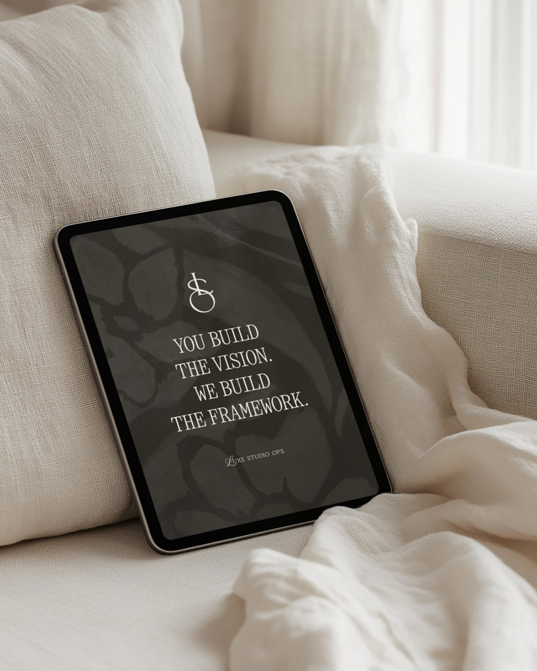 Digital tablet resting on a light-colored couch with fabric cushions, displaying a motivational quote in white text on a dark background.