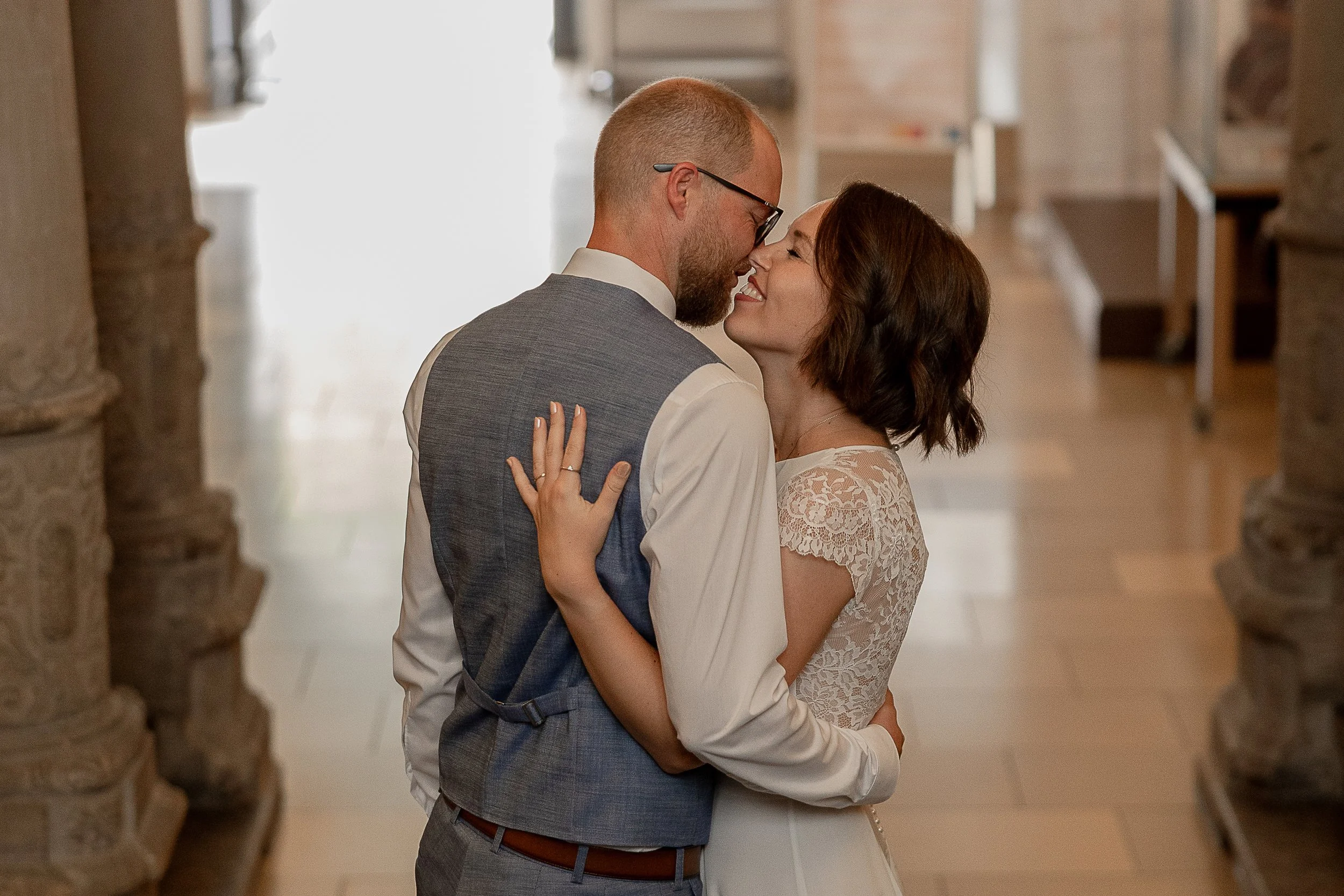 Ein Paar, das bei einer Hochzeit tanzt, steht sehr nah zusammen und lächelt sich an.