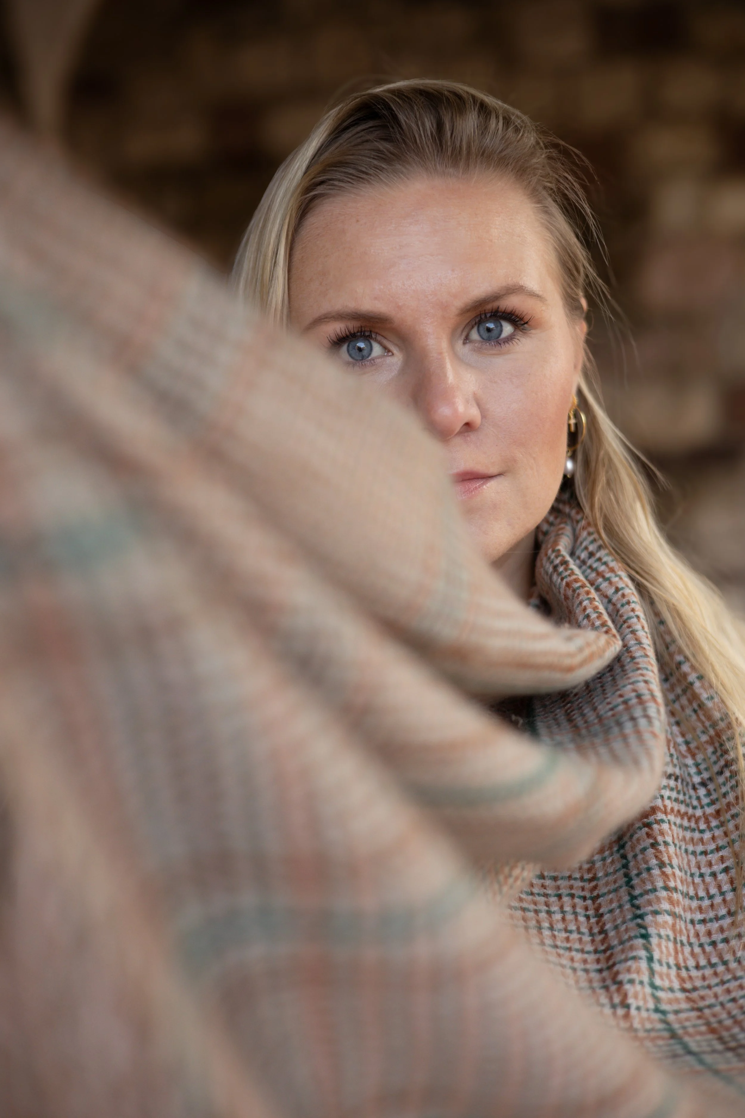 Nahaufnahme einer Frau mit blauen Augen, die an einem Schal und einem Pullover im Herbst gekleidet ist, im Hintergrund unscharf.