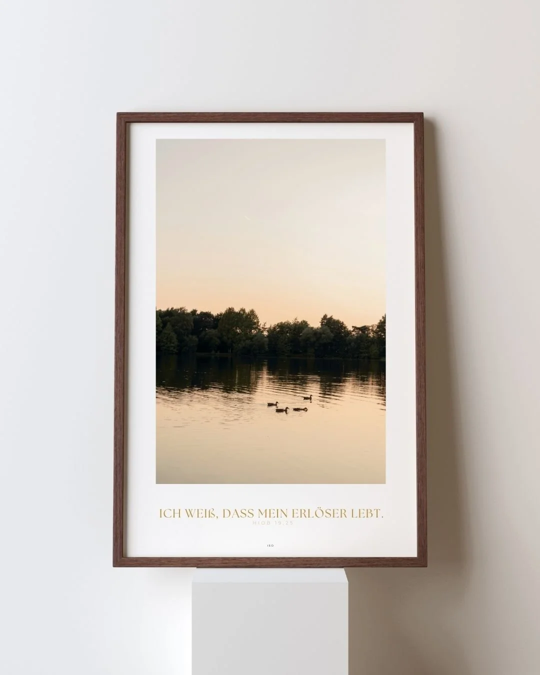 Ein Gemälde eines ruhigen Sees mit Baumgürtel im Hintergrund, drei Enten schwimmen auf dem Wasser, die Szene ist bei Sonnenuntergang. Unten ist ein deutscher Text, der sagt: 'Ich weiß, dass mein Erlöser lebt.'