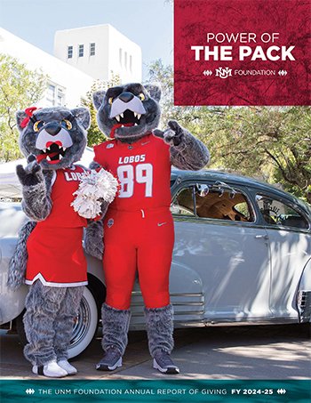 Two mascots dressed as wolf characters in red sports uniforms standing next to a silver car. One mascot holds a bouquet of flowers, with a banner over them that reads 'Power of the Pack' and the UNM Foundation logo. The background features trees and a white building.