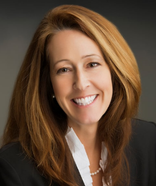 Portrait of a woman smiling with shoulder-length light brown hair, wearing a black blazer and white blouse.