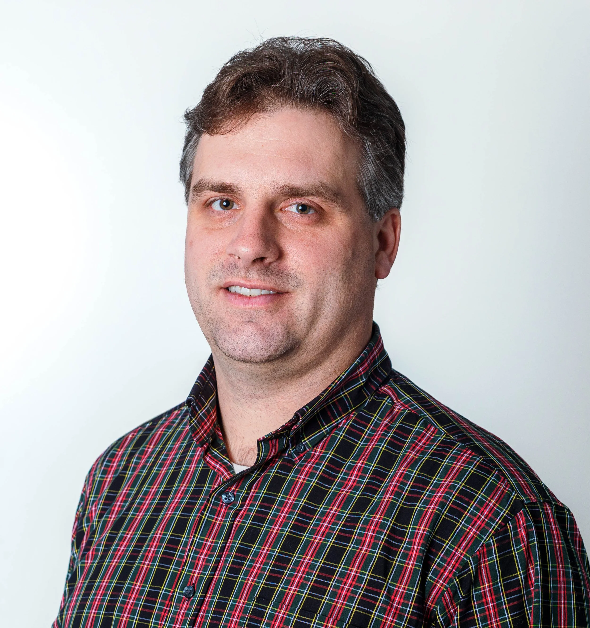 Sunset at the beach with colorful houses, a pier, and palm trees reflected in a small water stream.