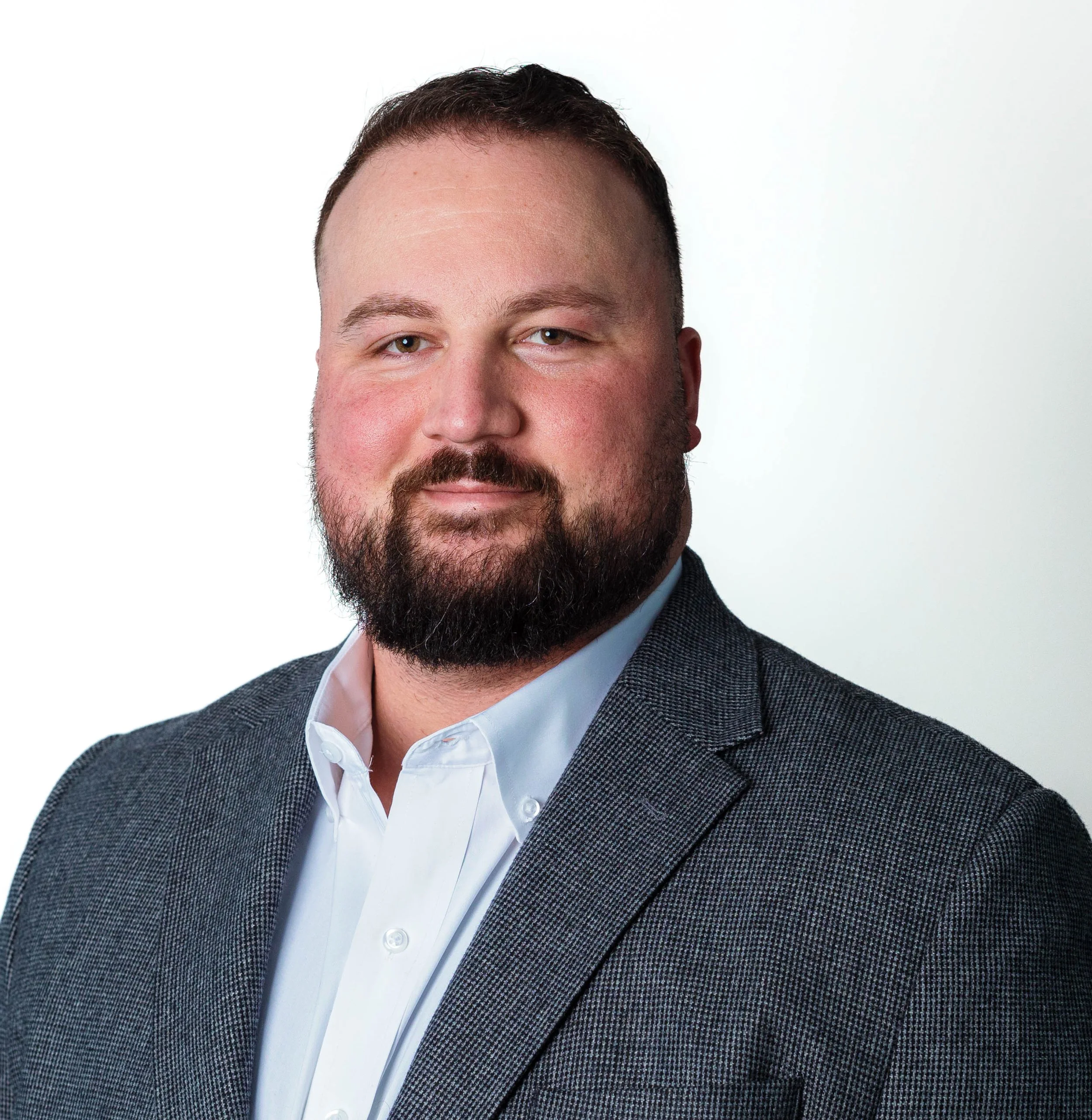A woman with short curly hair wearing glasses, hoop earrings, and layered necklaces smiling at the camera.