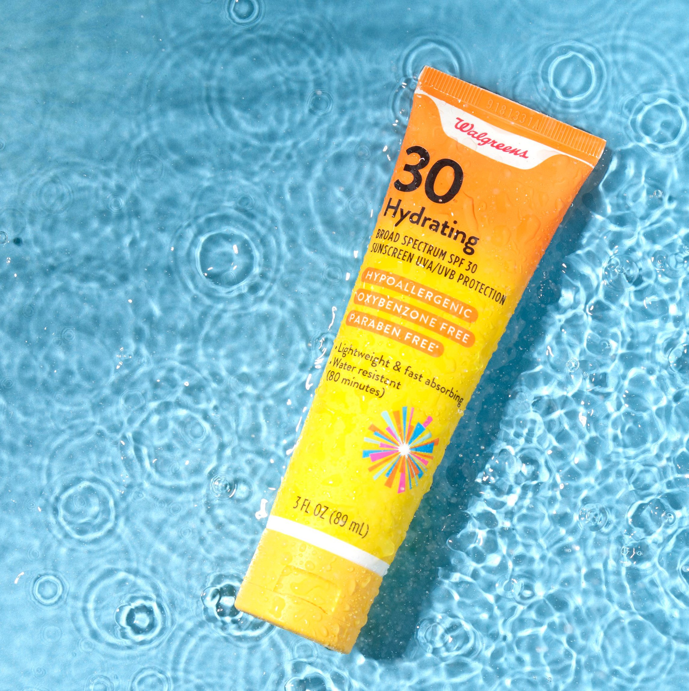 A tube of Walgreens broad spectrum SPF 30 sunscreen floating on water with ripples.