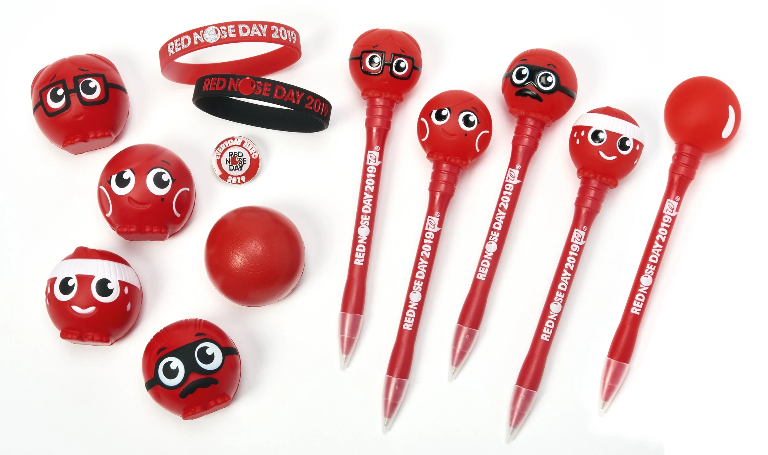Collection of red themed stationery items and accessories for Red Nose Day 2019, including pens with emoticon faces, wristbands, stickers, and a small red ball.