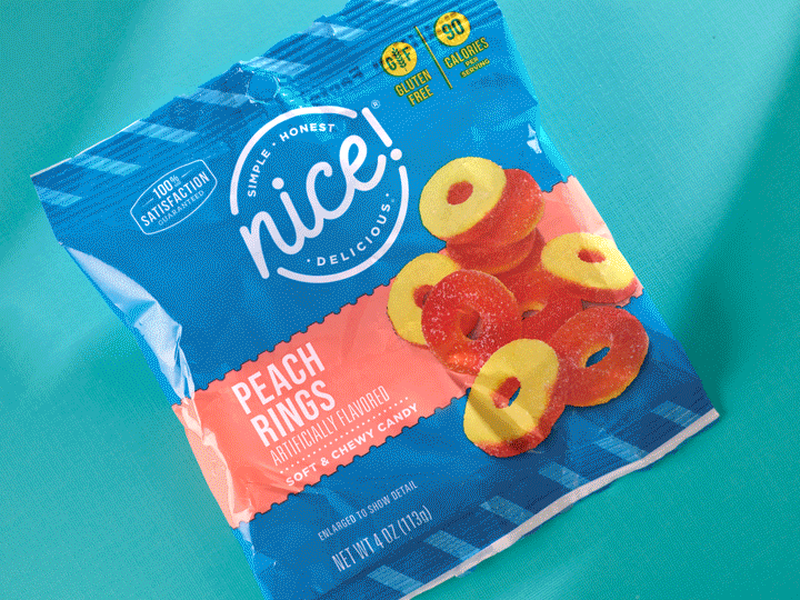 A bag of Nice Peach Rings candy on a blue surface, featuring images of peach ring candies and text indicating it is gluten free, with 90 calories per serving.