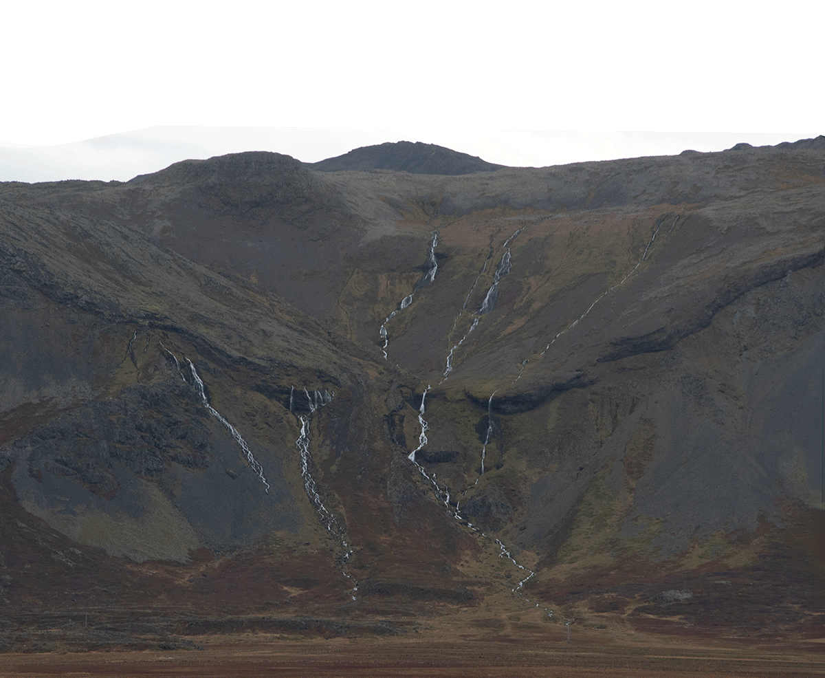 A mountainous landscape with multiple small waterfalls cascading down the slopes, sparse vegetation, and an overcast sky.