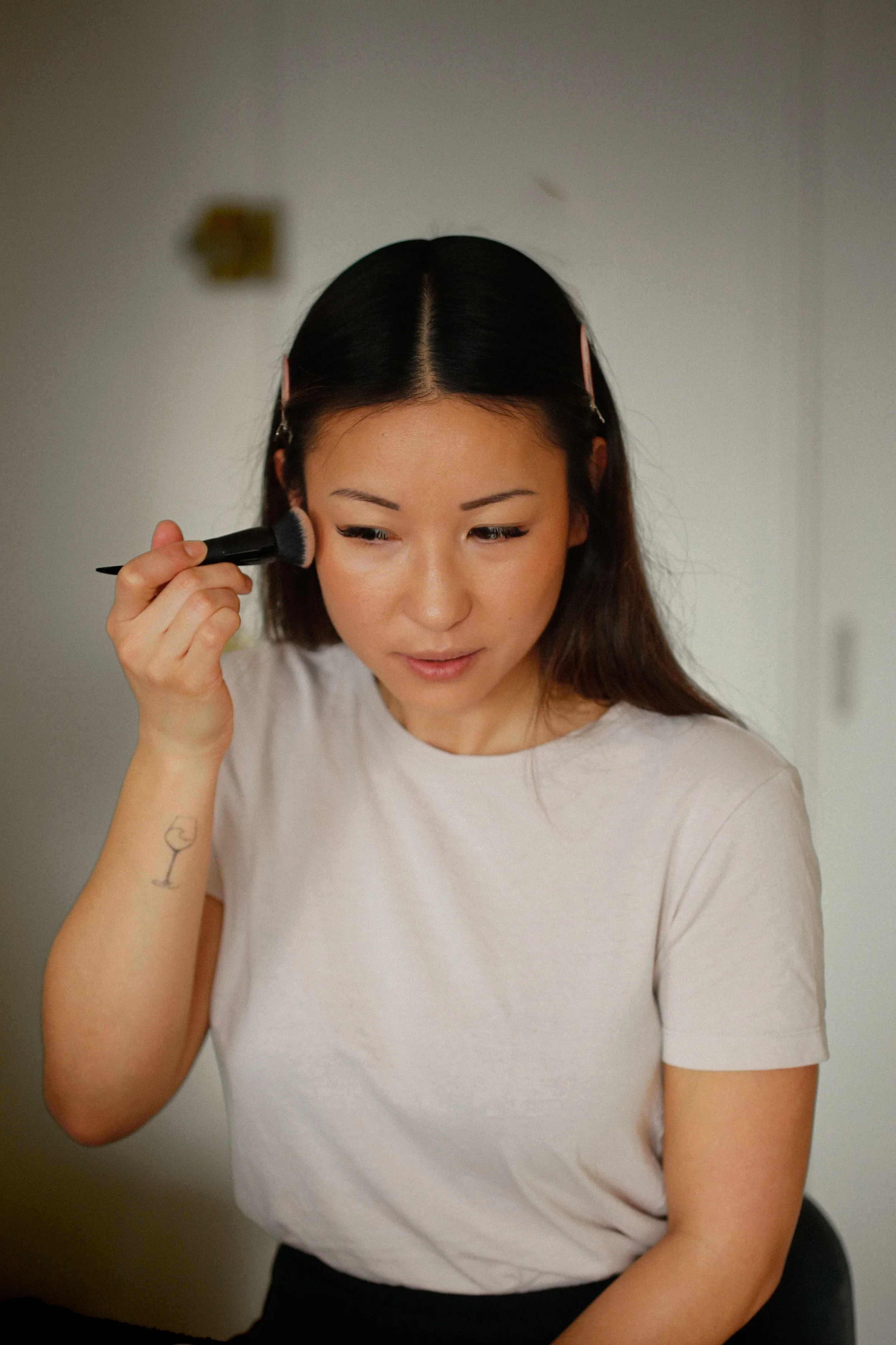 Jeune femme asiatique se maquillant avec un pinceau lors d'un cours de maquillage avec un maquilleuse professionnelle en Vendée.