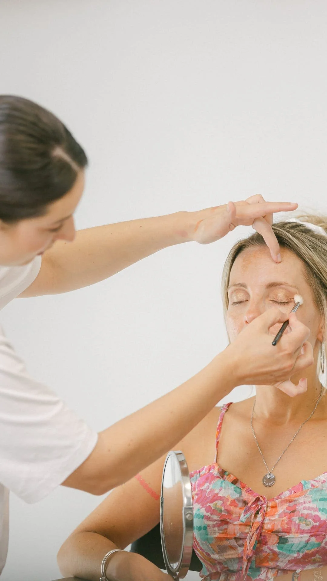 Une femme se fait maquiller les yeux par une maquilleuse dans un studio de maquillage.