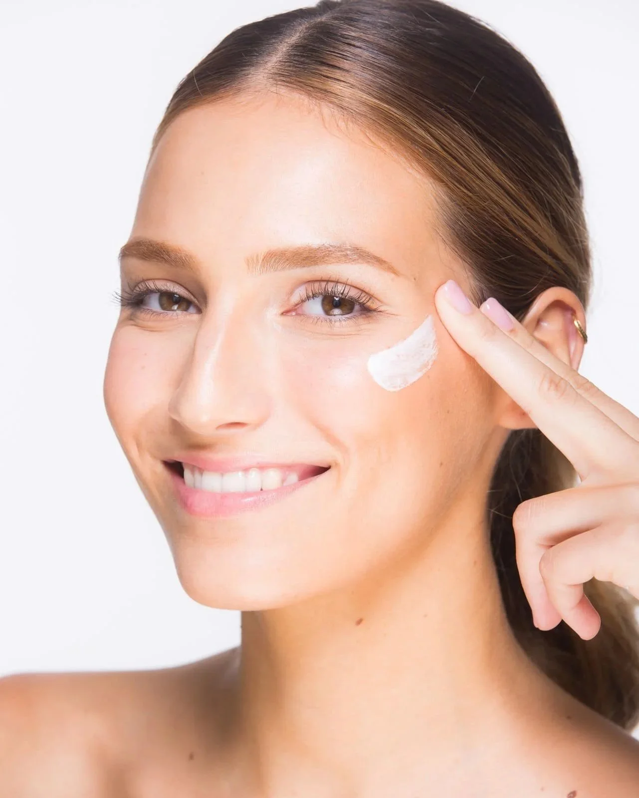 Modèle professionnelle pour une marque soin applique de la crème sur son visage