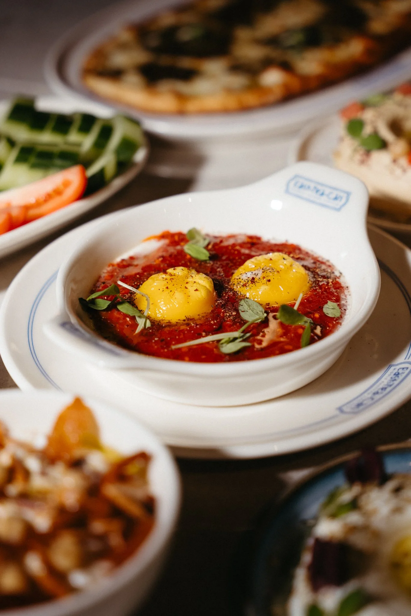 Two eggs in tomato sauce garnished with herbs, served in a white dish.