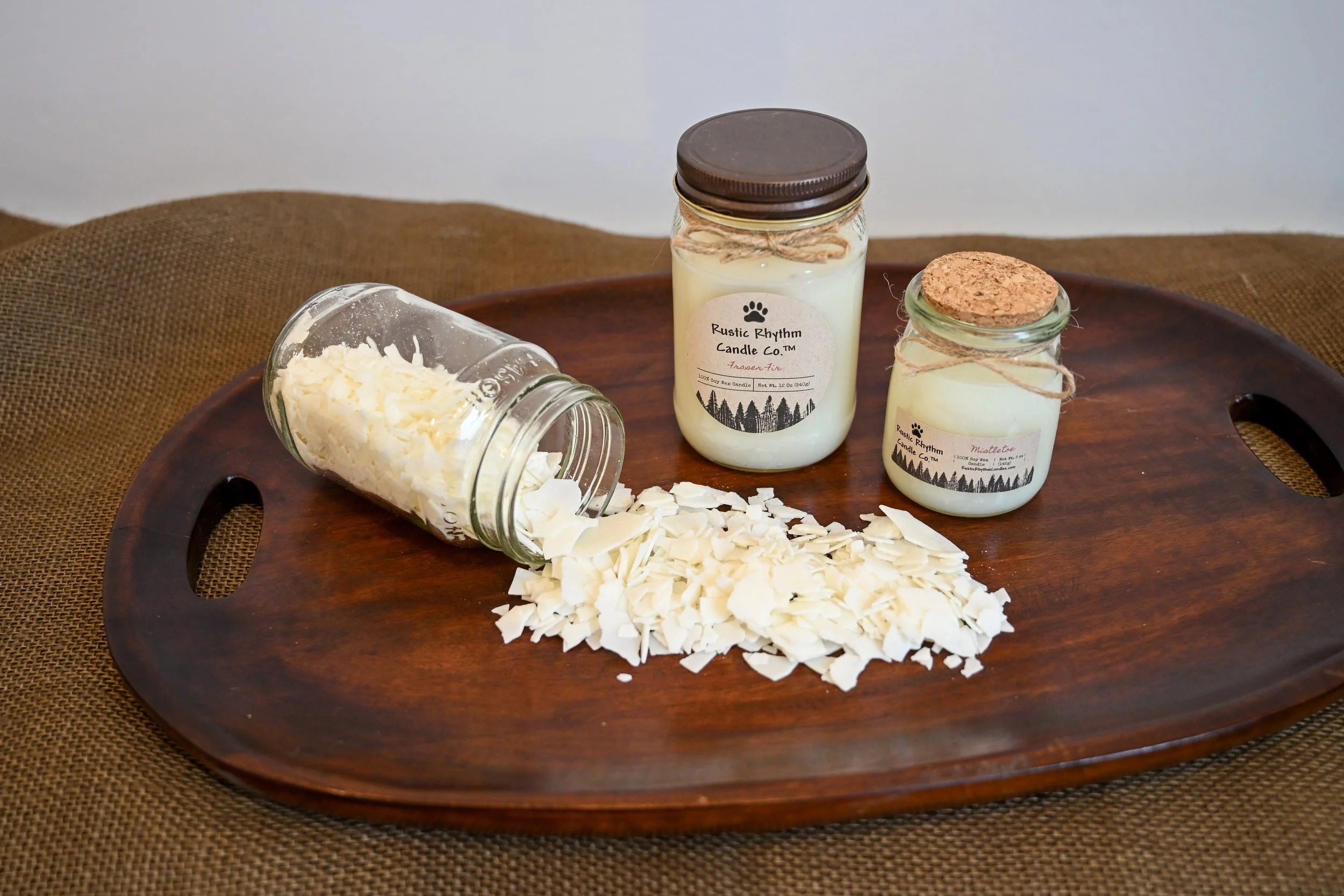Two Rustic Rhythm Candle Co.™ candles displayed on board with raw wax