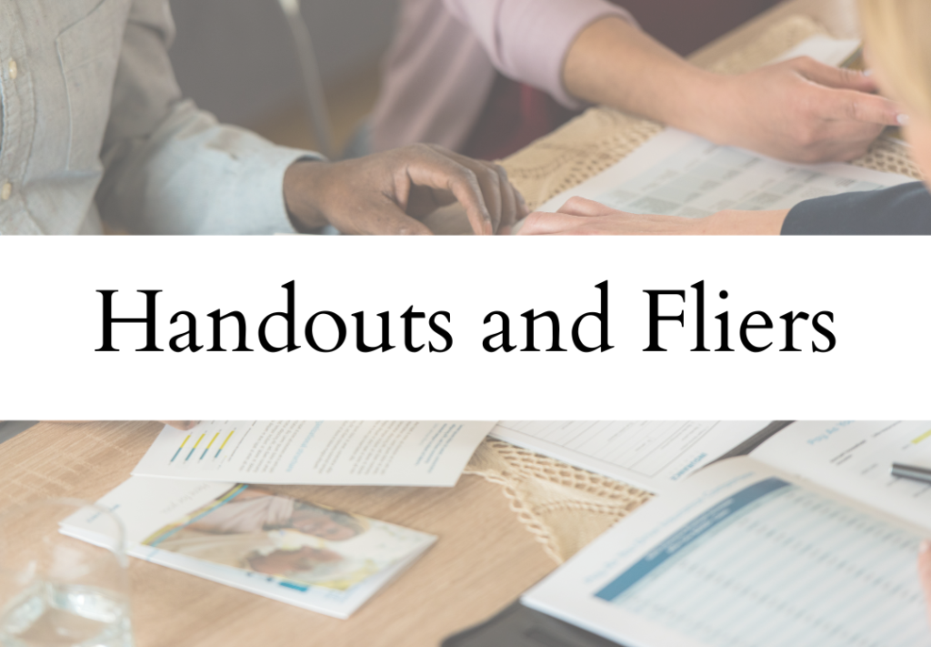 People working at a table with handouts, flyers, and printed documents.