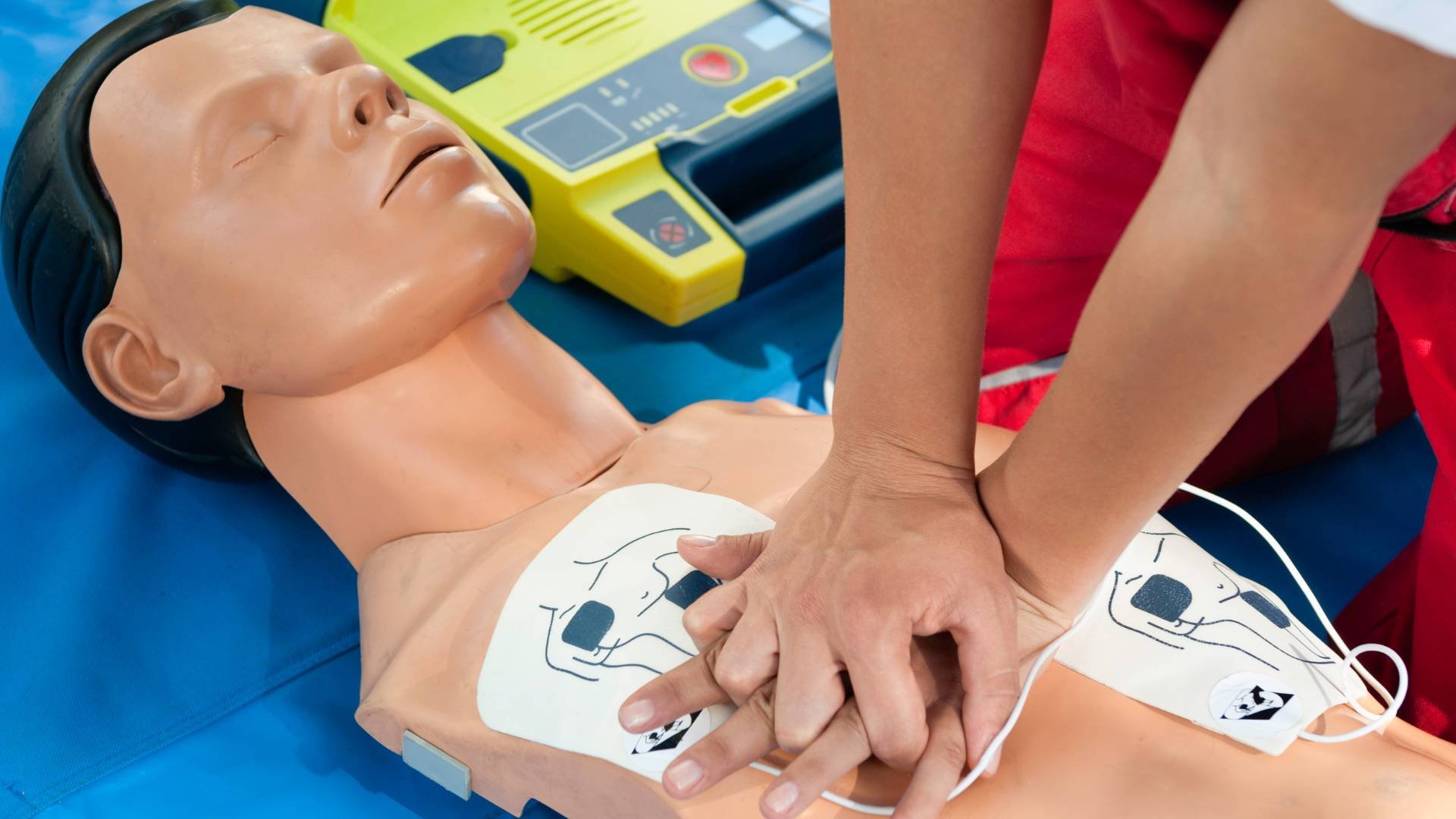 Rescue worker performing CPR on a medical training mannequin during a training session.