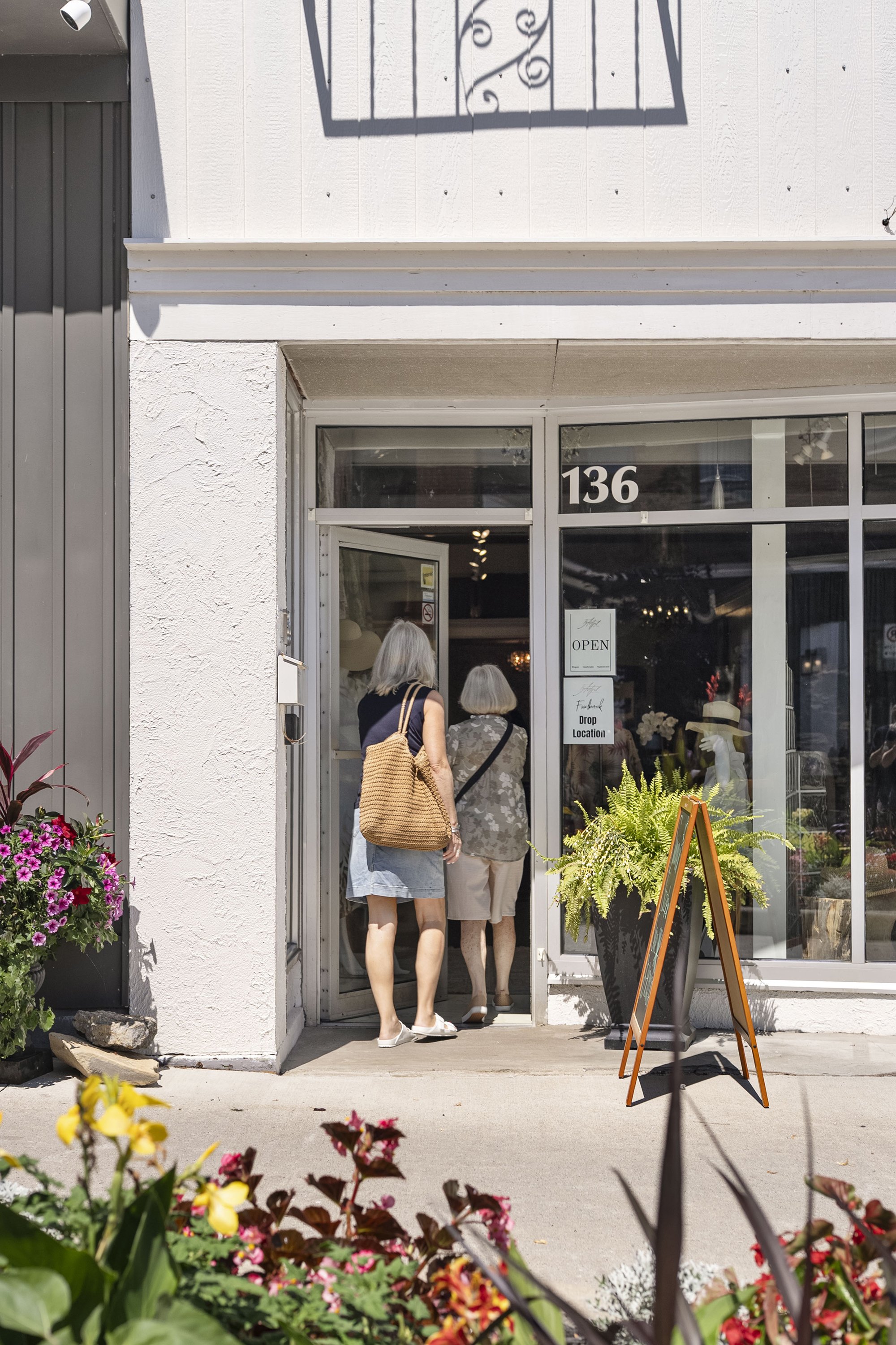 Two women entering the glass front doorway of a store