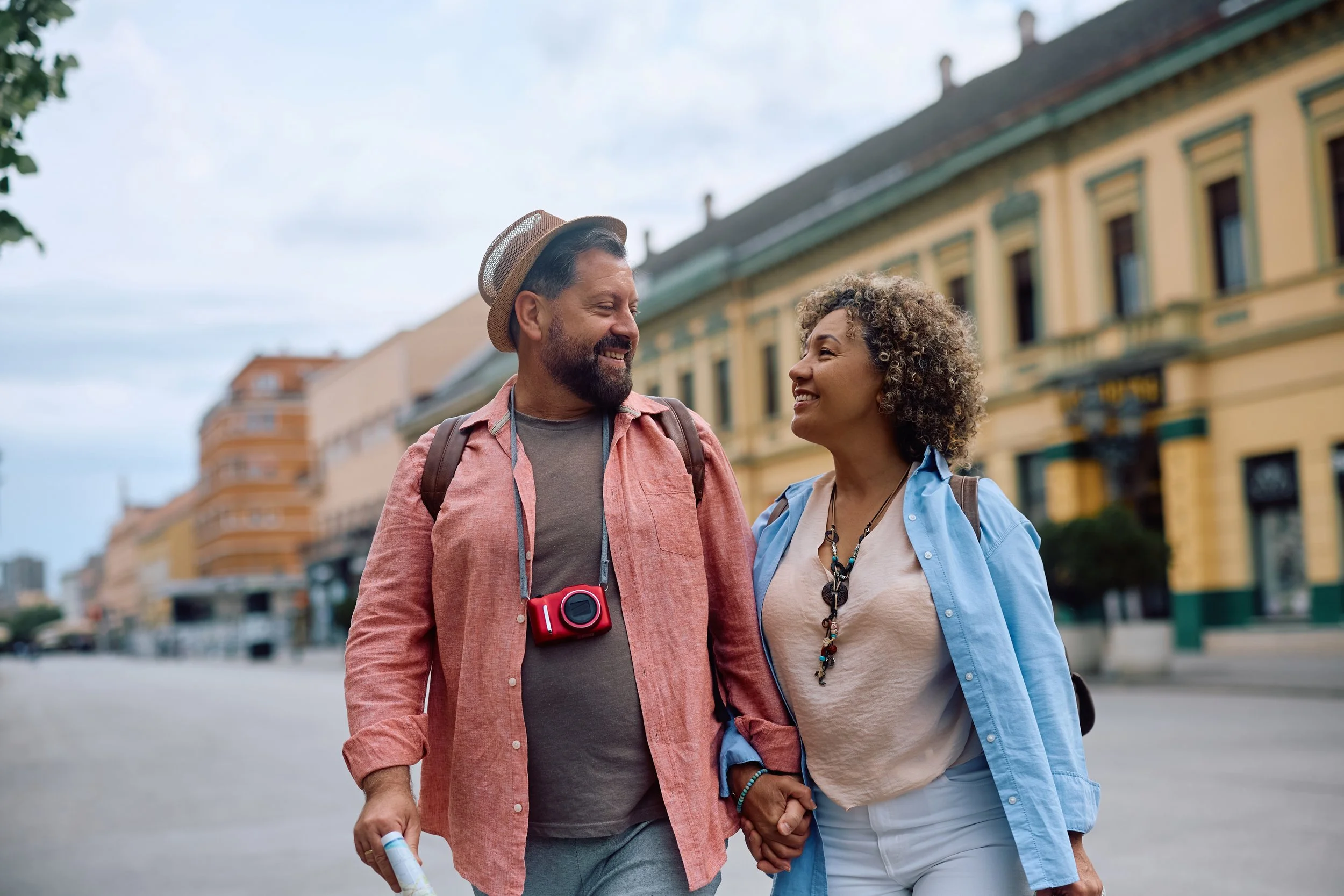 A mixed-race mature couple on vacation, holding hands and smiling