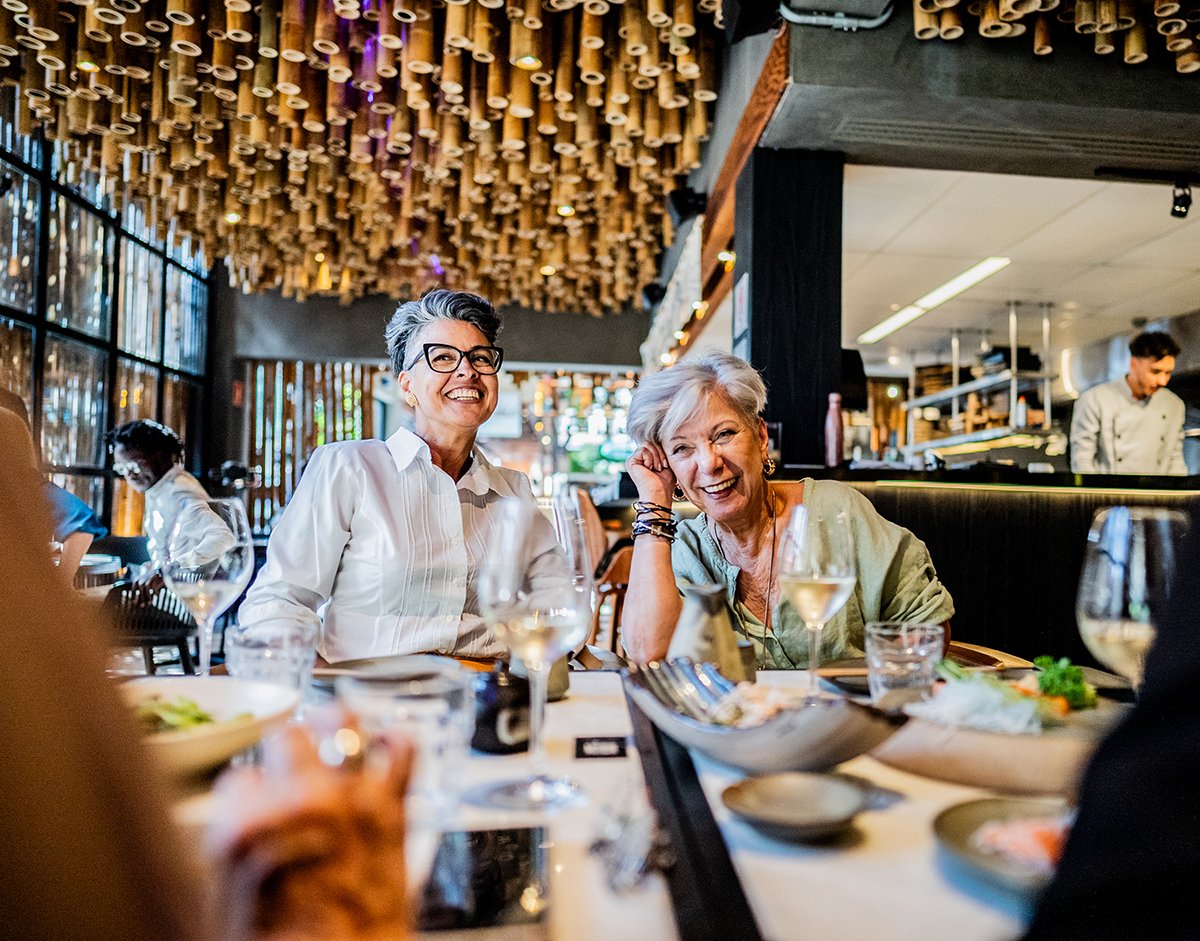 Two gray-haired mature ladies laugh during an expensive lunch with friends