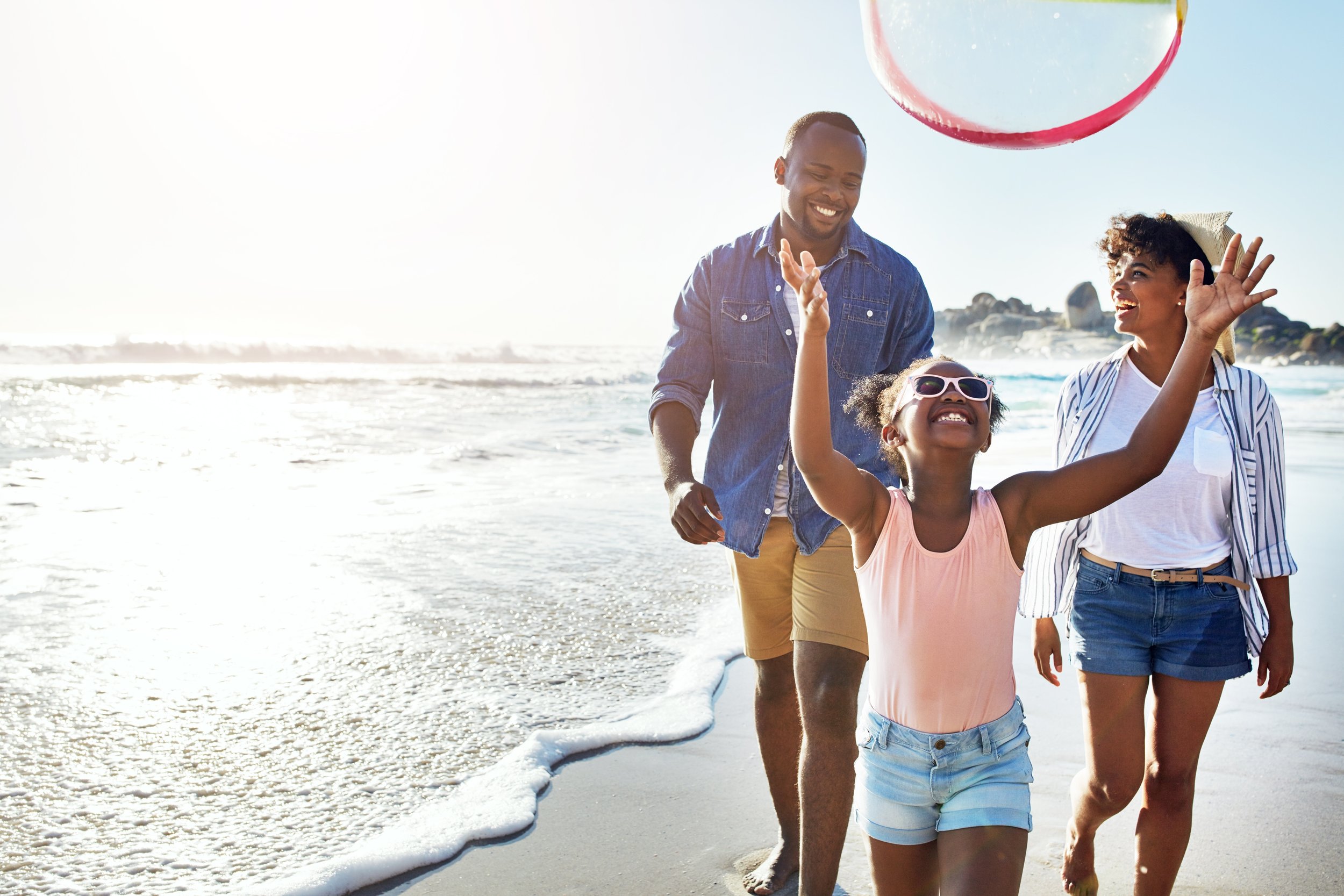 A young African-American couple walks on the beach with their daughter.