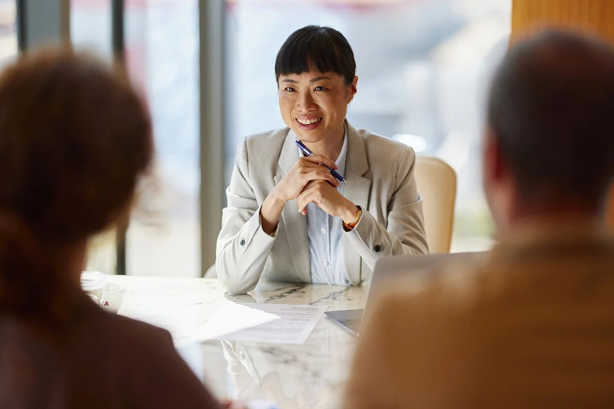 A mature Asian female financial professional meeting with clients
