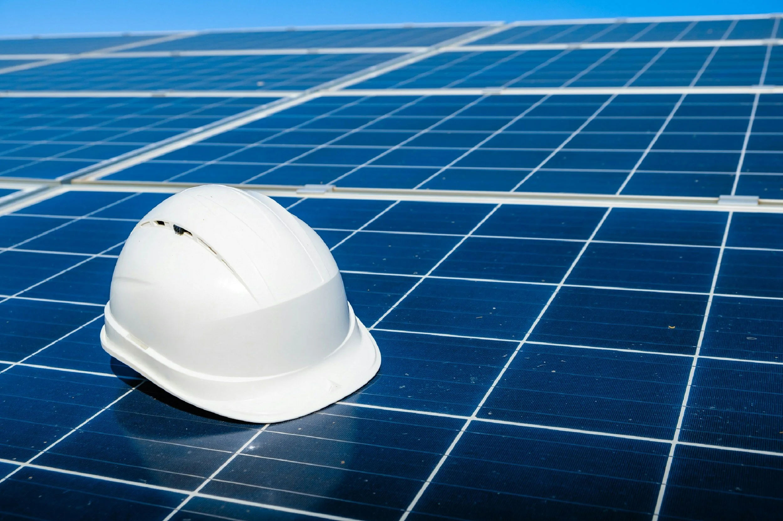 A white safety helmet resting on a large array of blue solar panels.