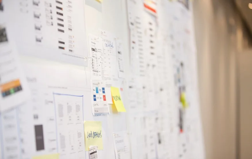 Bulletin board with various papers, charts, and sticky notes attached.