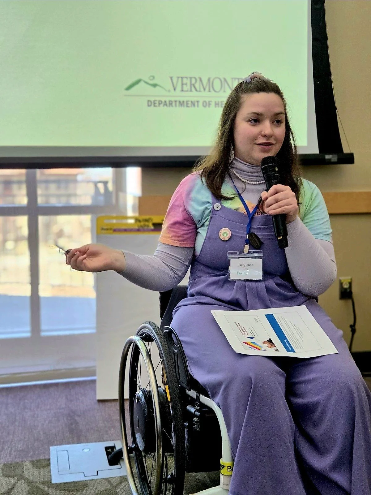 Young woman with long brown hair presenting at the 2025 Translating Identity Conference.