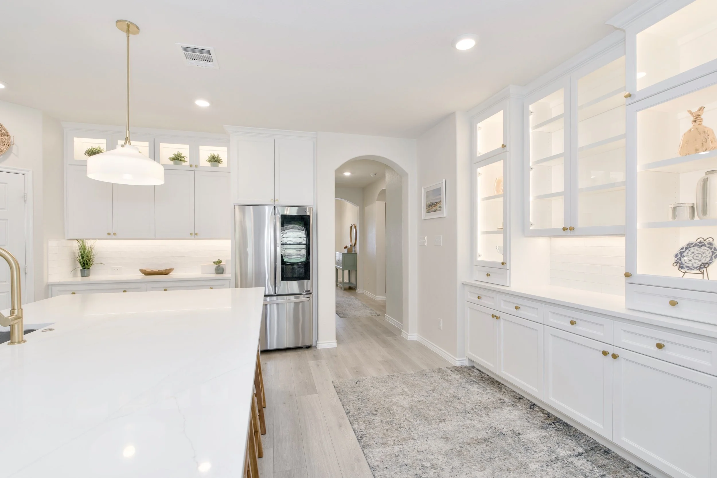 Custom, built-in china hutch with glass front doors to display special dishware or decor pieces. LED lighting in and under cabinetry with quartz countertop below center cabinet above.