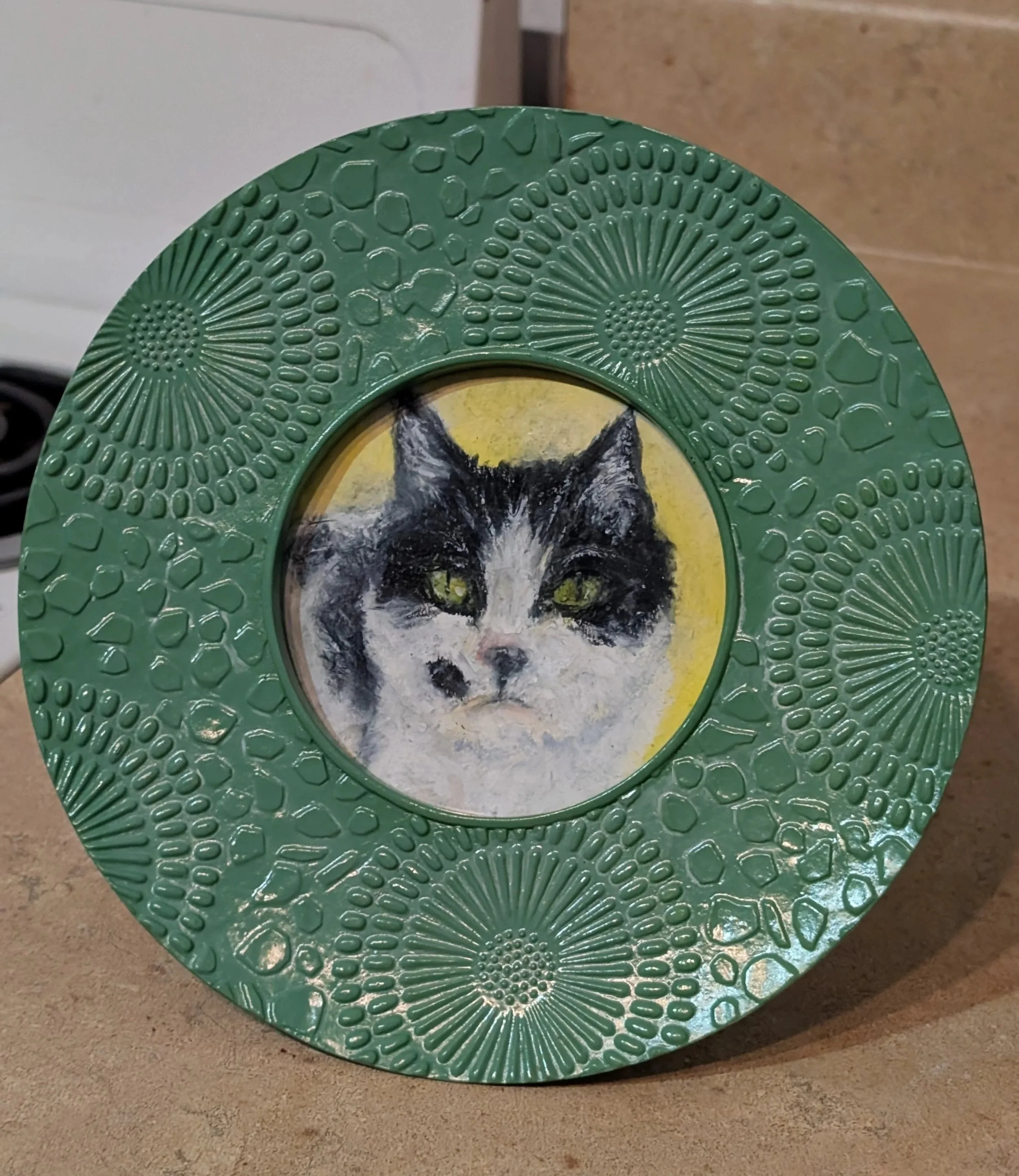 Small pet portrait of a tuxedo cat within a green circular frame
