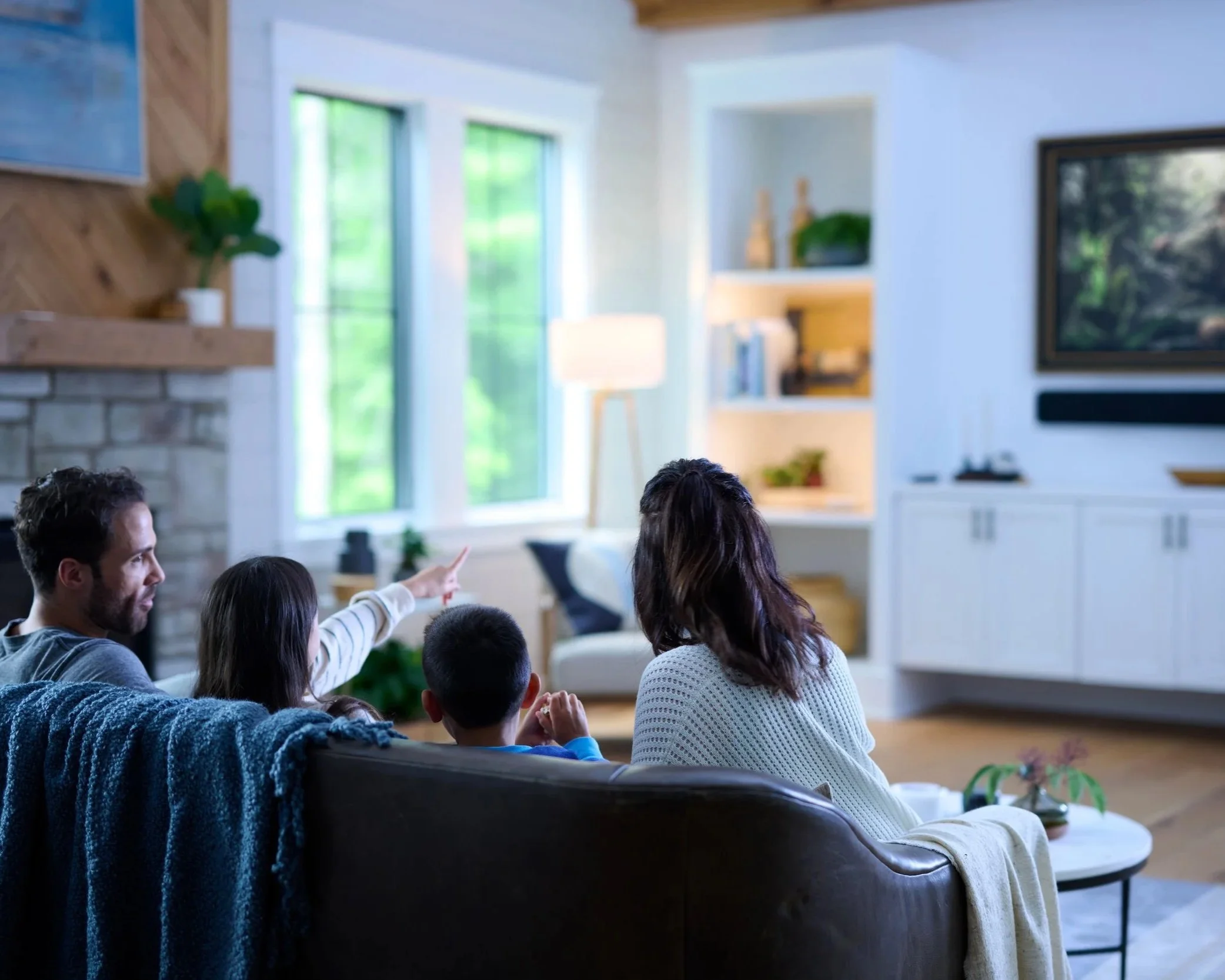 Family watching television together in a cozy living room with integrated whole-home audio and video”